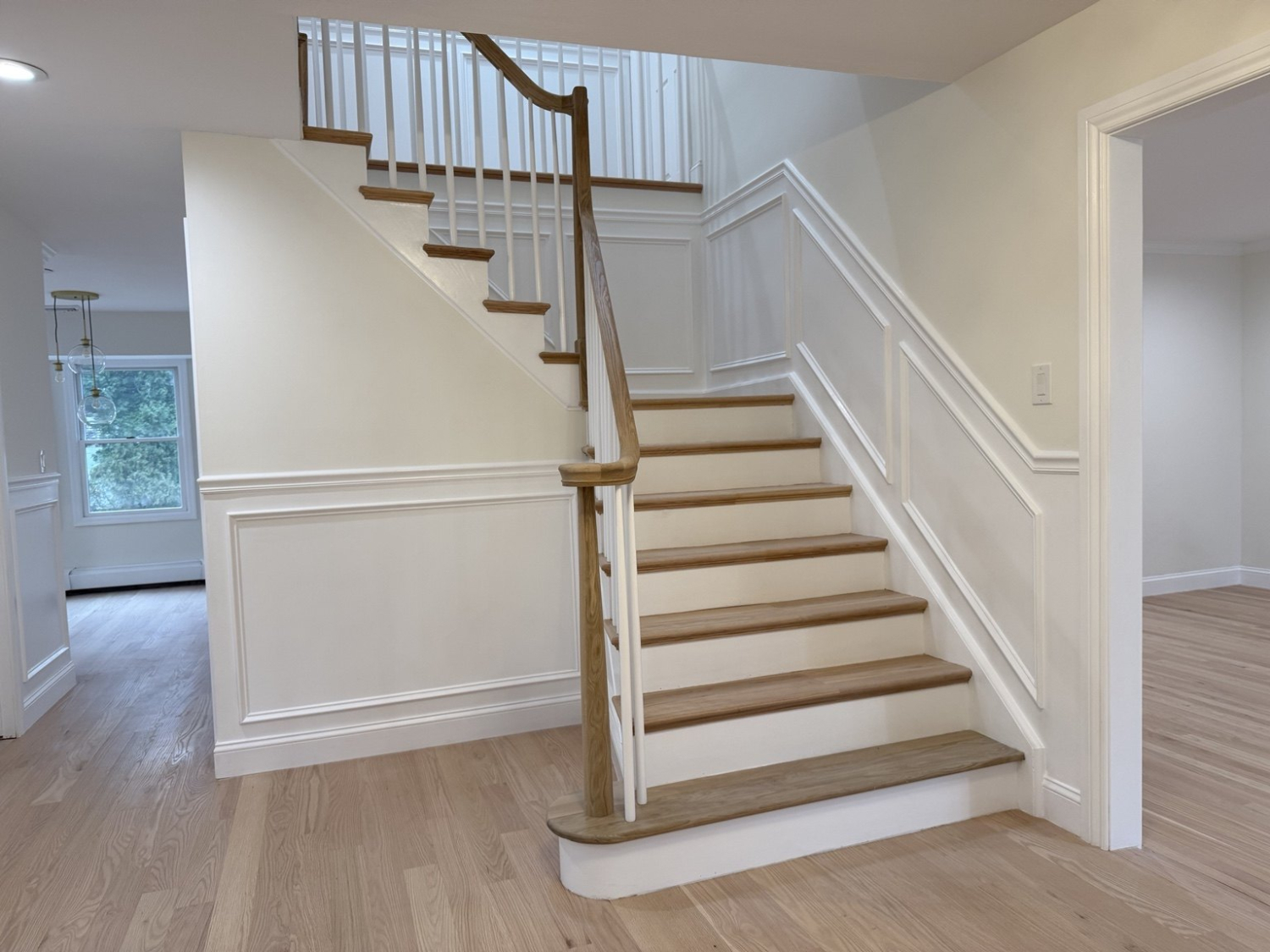 After: Dix Hills wood staircase with white balusters and decorative wall trim
